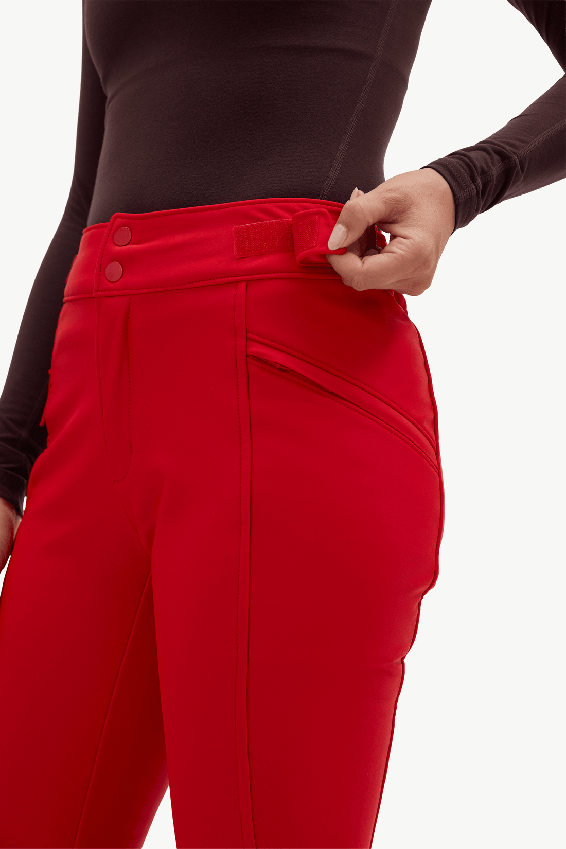 A model shown from the back wearing bright red flared pants, a dark brown long-sleeve top against a plain white studio background.
