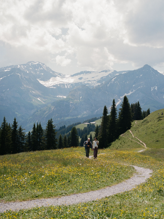 Two girls in a field, hiking near a mountain range 