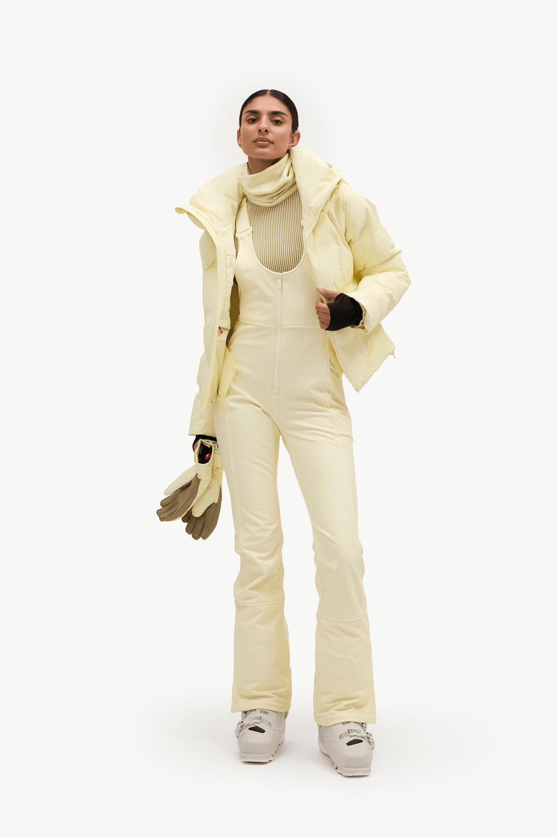 A woman wearing a pale pastel yellow puffer jacket and matching light pants against a clean white studio background.