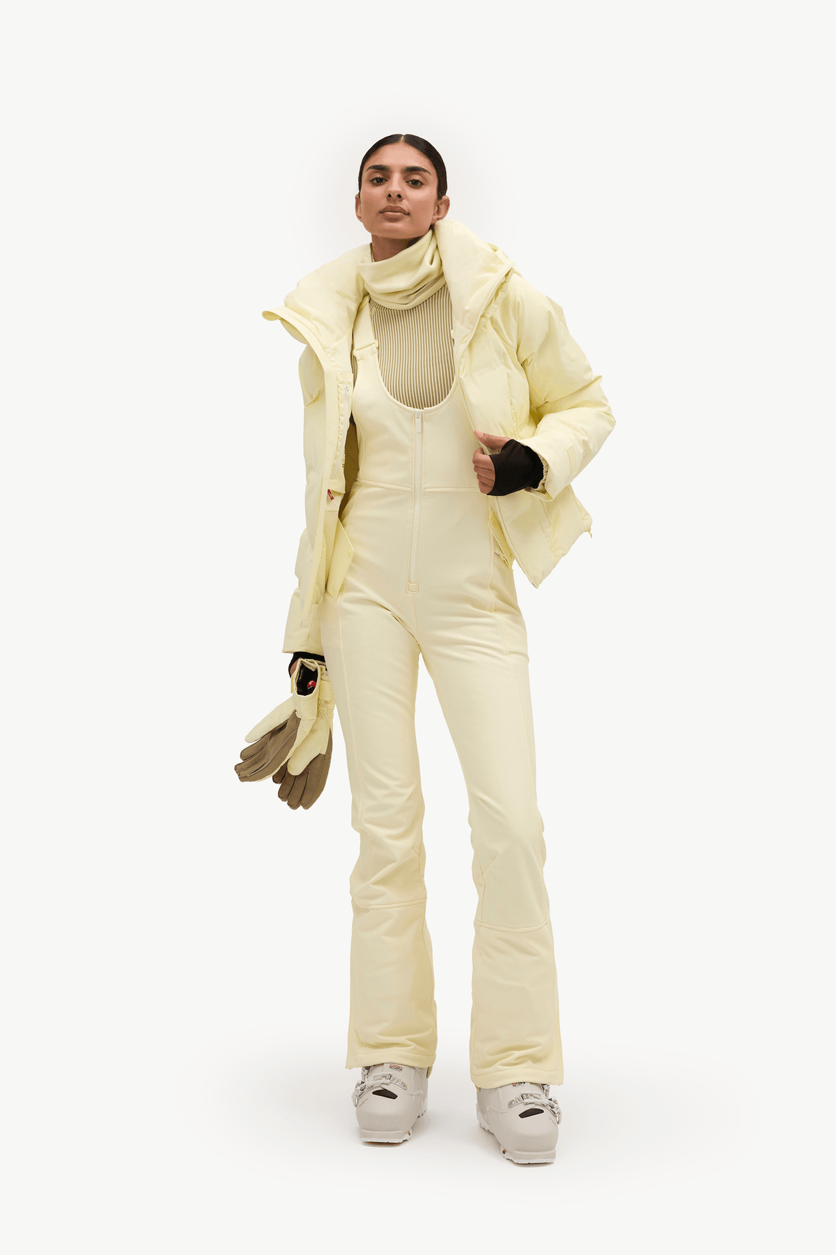 A woman wearing a pale pastel yellow puffer jacket and matching light pants against a clean white studio background.