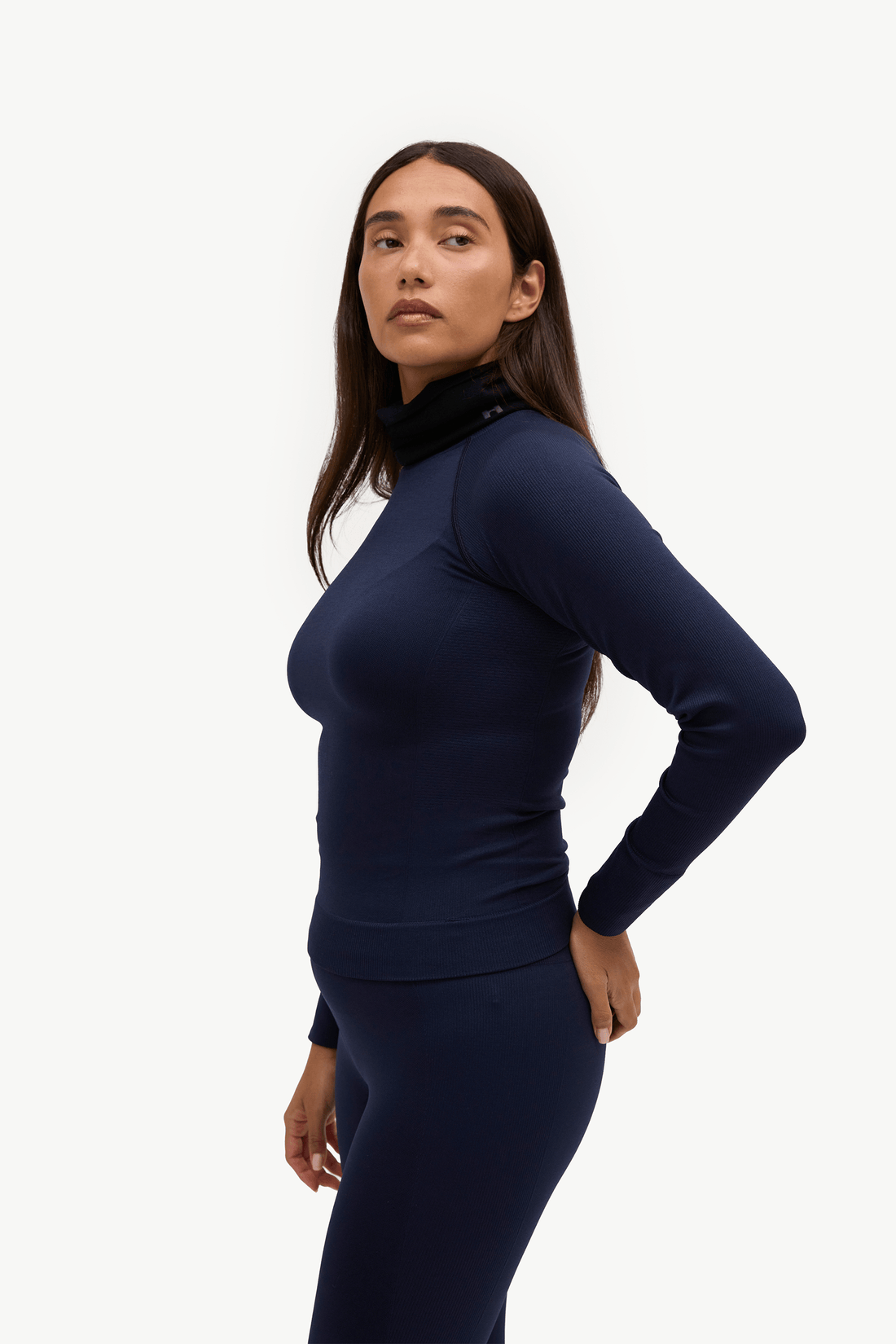 A woman modeling a dark navy blue long-sleeve athletic top and matching leggings against a plain white studio background.
