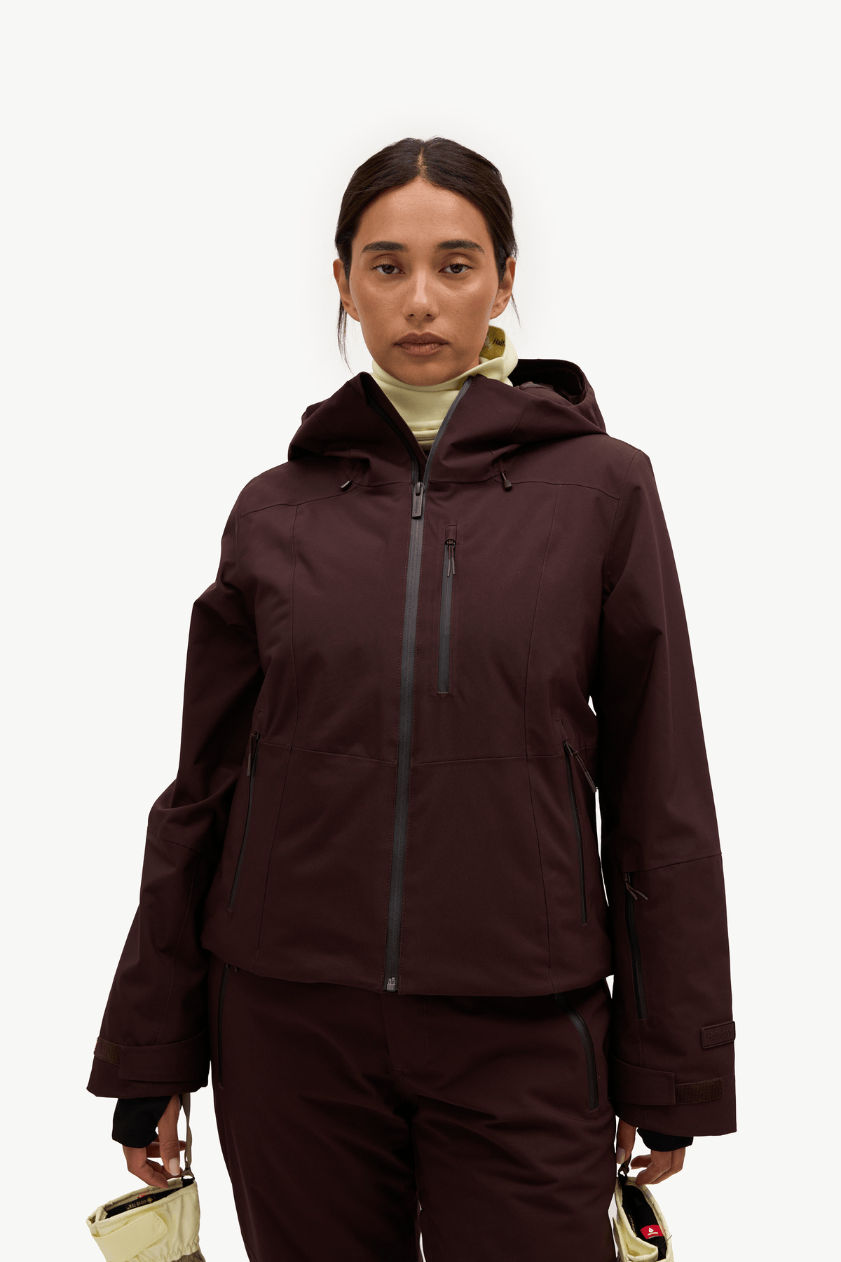 A woman modeling a dark plum hooded jacket and matching pants against a clean white studio background.