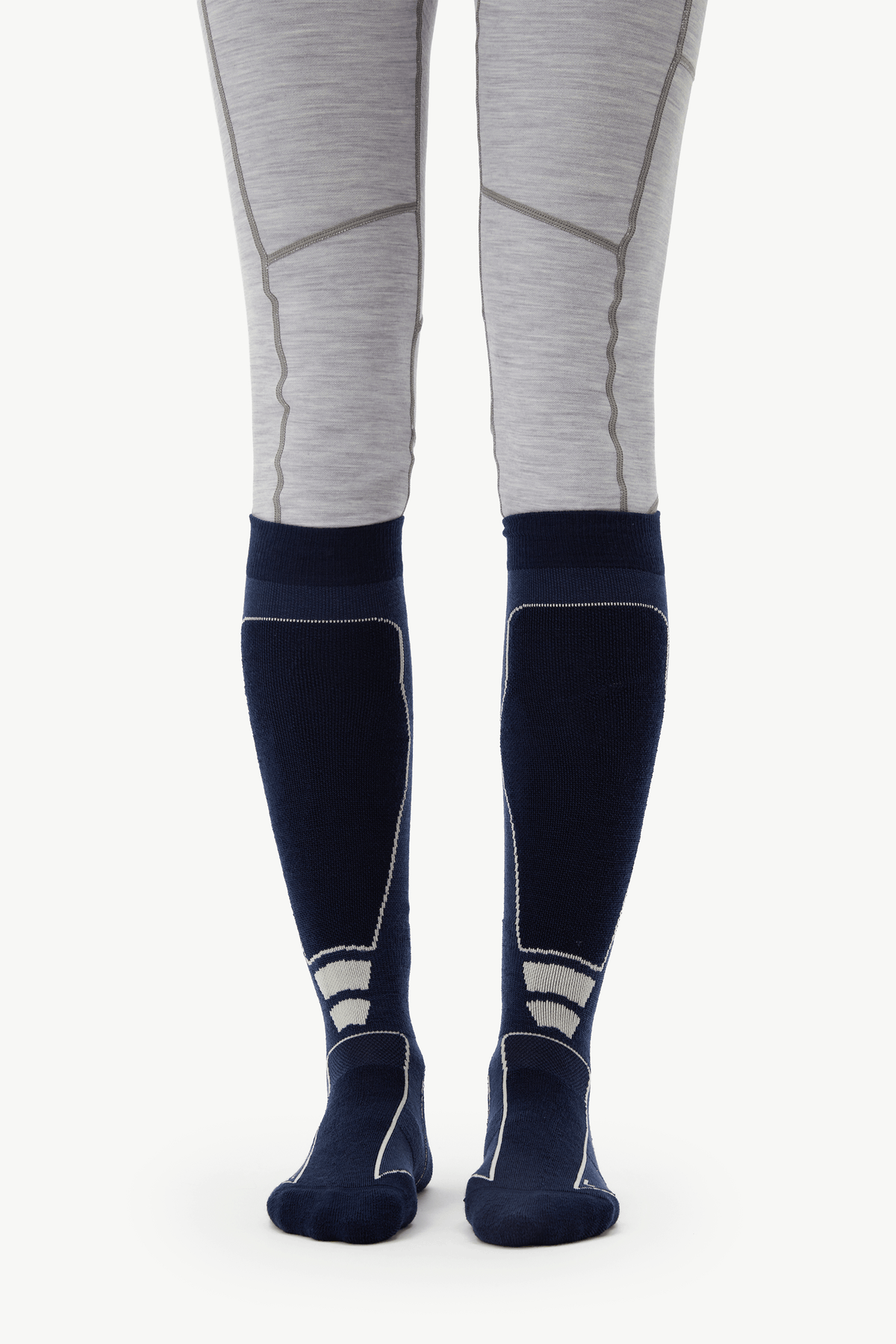 A pair of navy blue knee-high compression socks with light gray and white paneling, worn with light gray heathered leggings on a model's legs, shown against a plain white background.