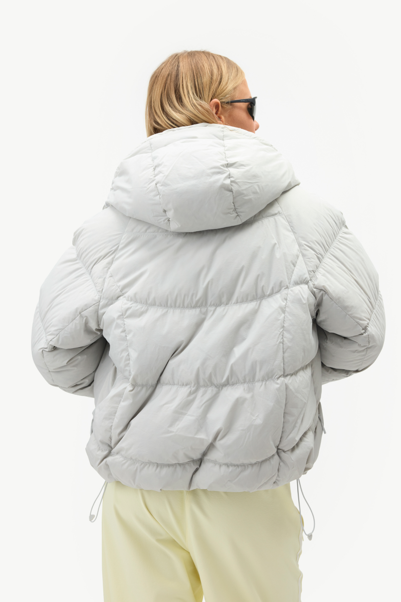 Back view of the light gray Louise Down Jacket showing the oversized hood, quilted construction, and adjustable hem.