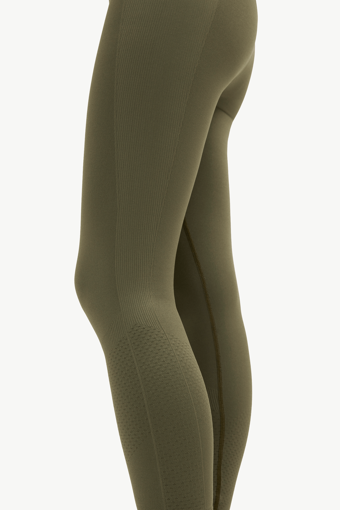 Close-up side view of a person wearing ribbed full-length leggings in an olive green color against a plain light background.