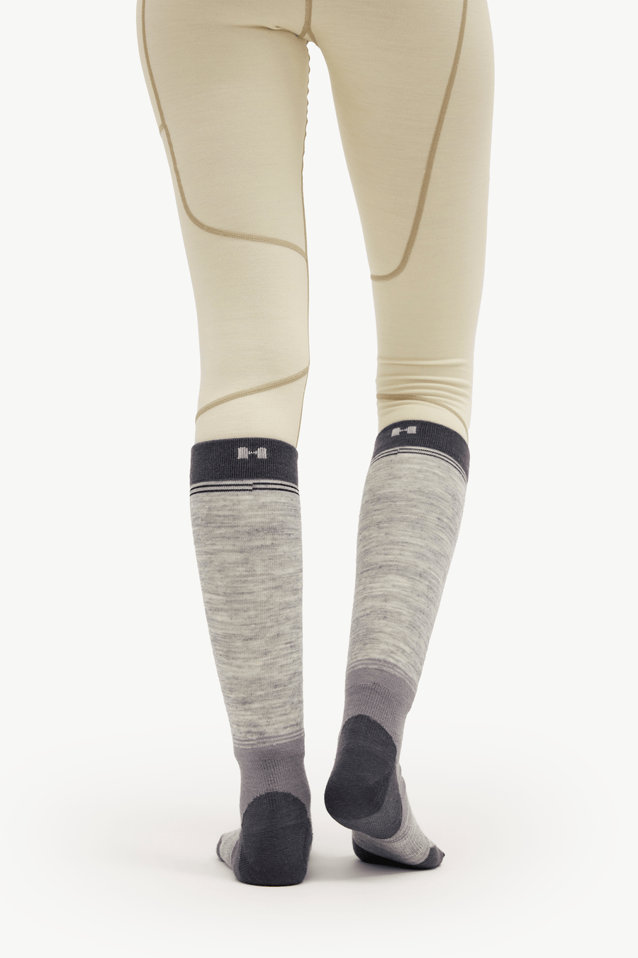 Gray heathered knee-high compression socks with dark gray heels, toes, and cuffs, worn by a model in beige riding tights against a white studio background.