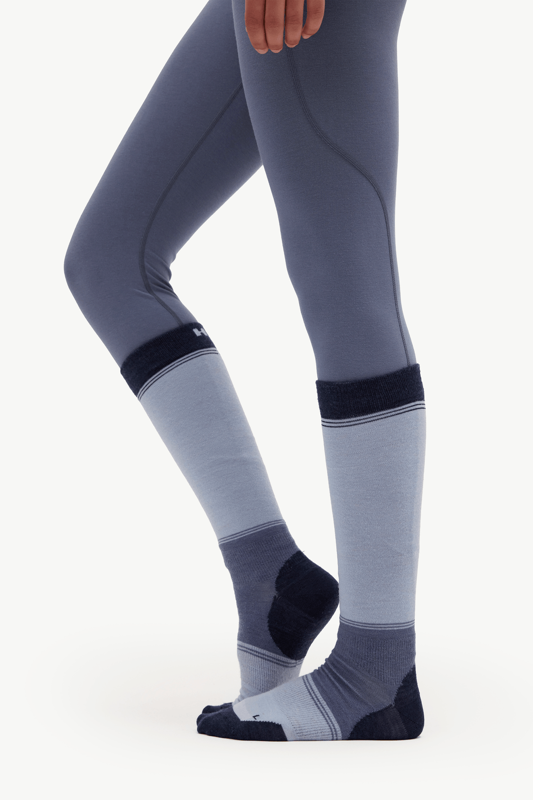 A person wearing gray and navy blue compression socks with matching gray leggings, shown from the knees down against a clean white background.